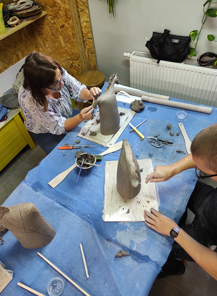 Zdjęcie: uczestnicy zajęć podczas lepienia ceramicznego barana