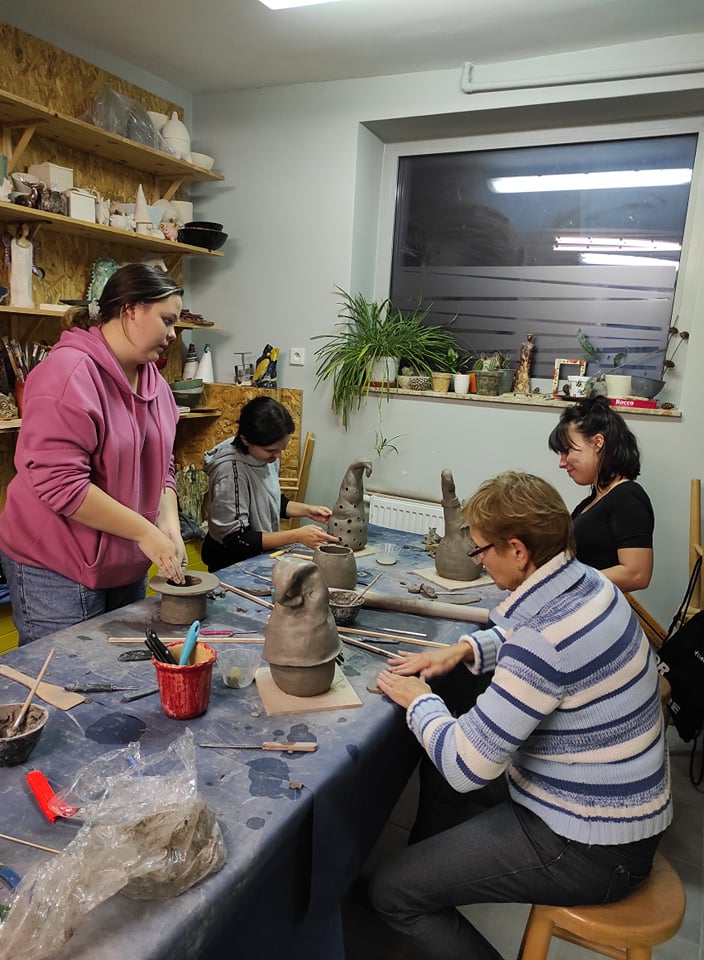 Zdjęcie: Pracownia ceramiczna. Cztery kobiety siedzą przy stole i lepią przedmioty.