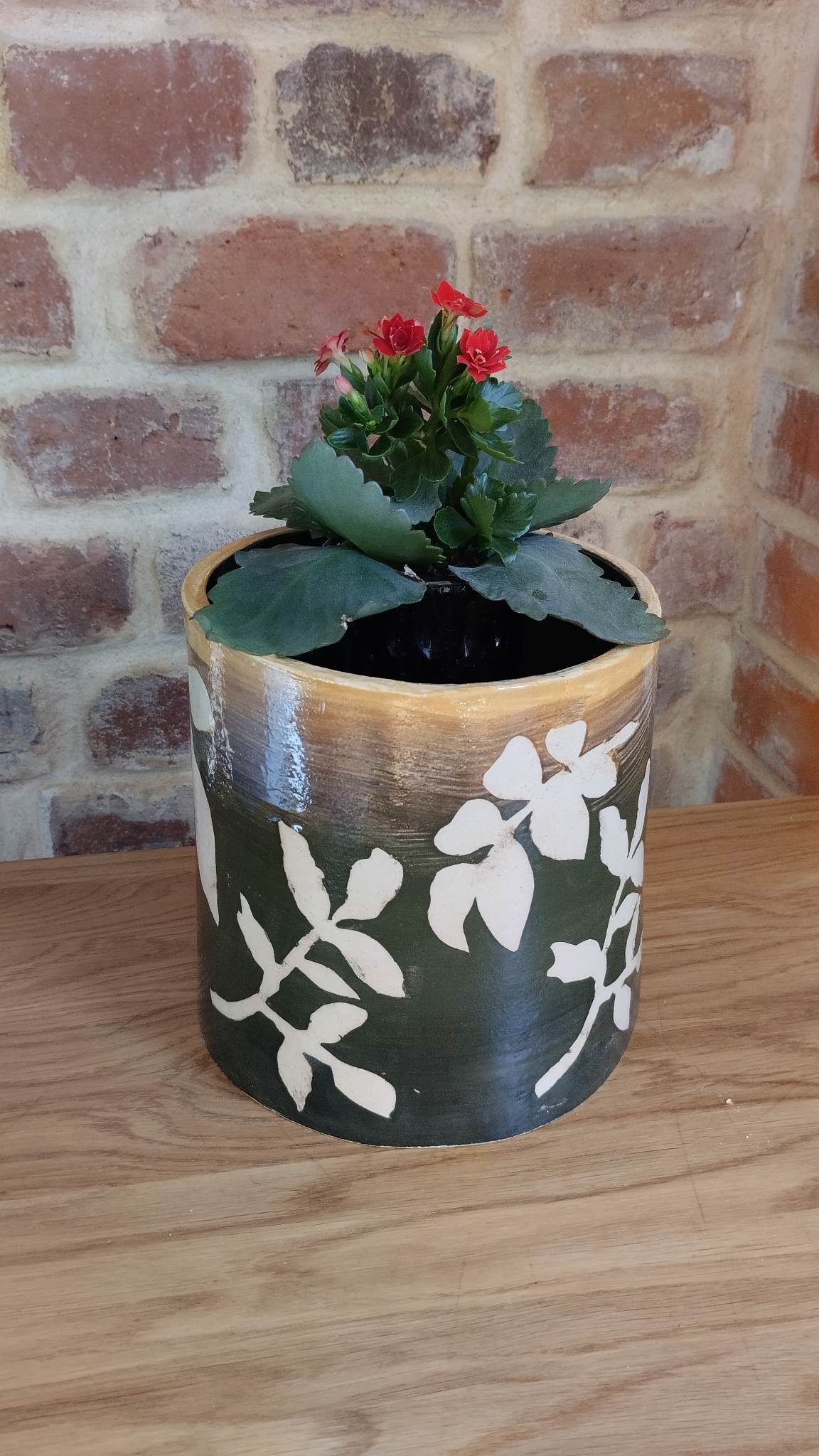 Ceramiczna doniczka z posadzonym kwiatkiem.