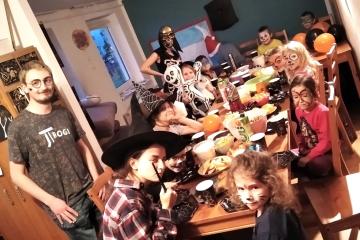 Dzieci w przebraniach halloweenowych siedzące przy stole 