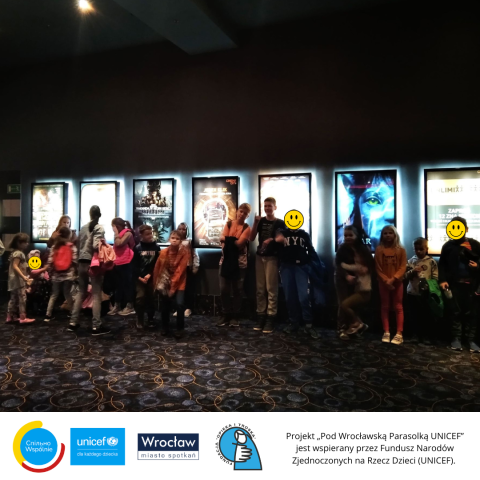 Grupa dzieci w kinie, na tle plakatów filmowych 